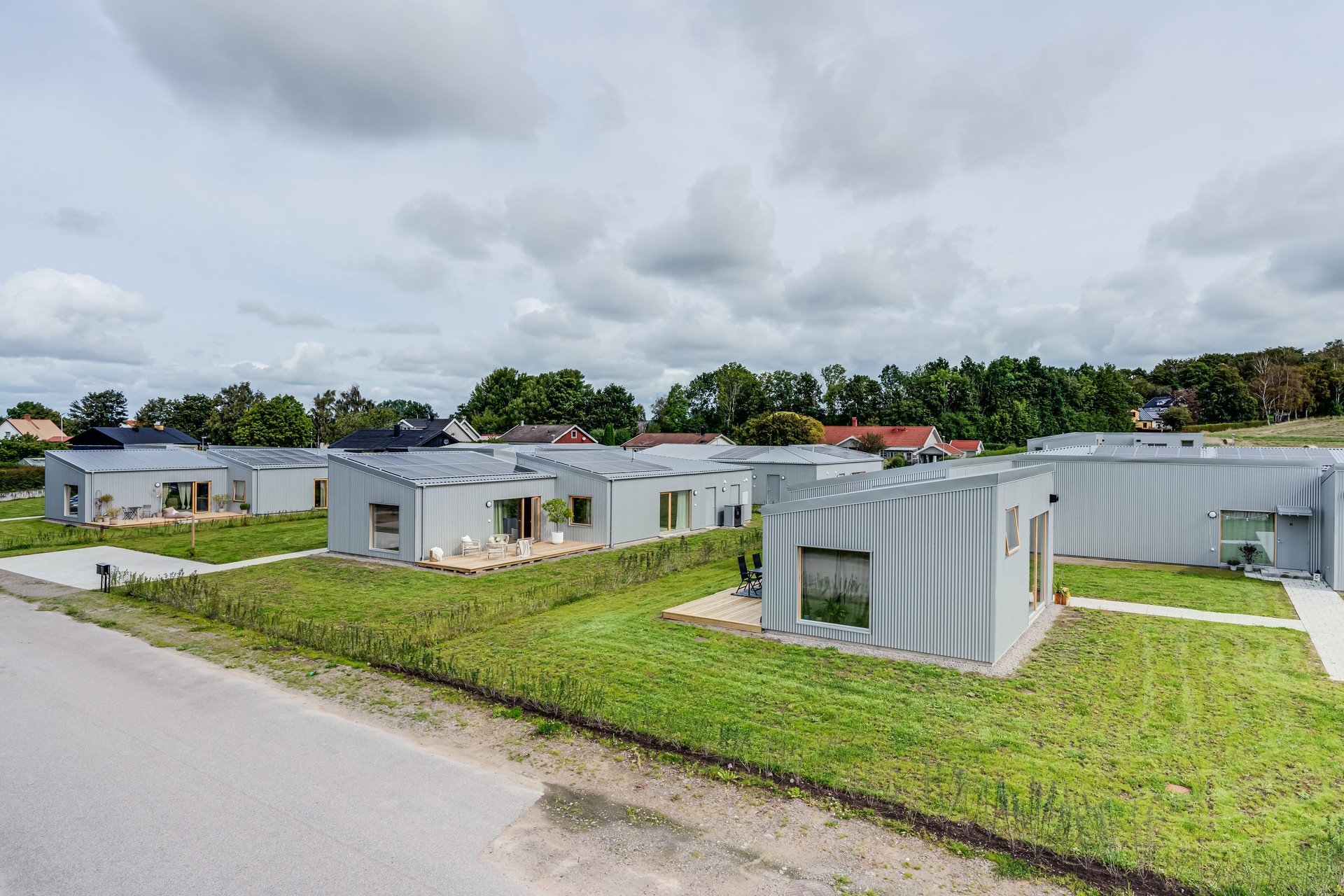 Modernt bostadsområde med stiliga hus omgivna av grönska och relaxytor.